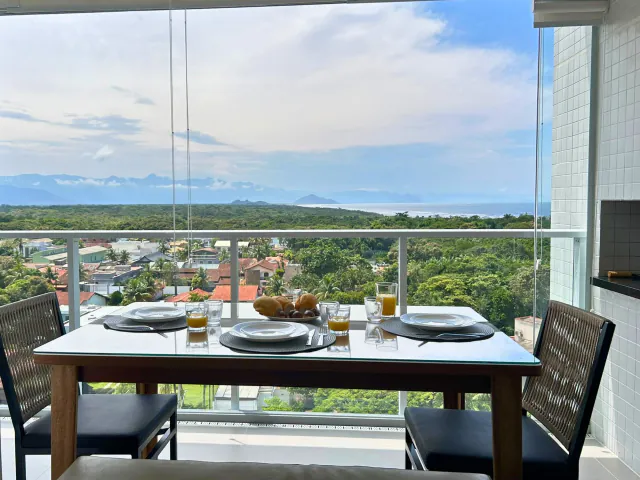 Mesa posta na varanda com vista para a mata e o mar