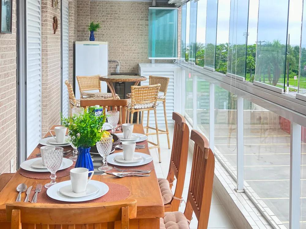 Mesa de café posta na varanda envidraçada, com vista para o mar